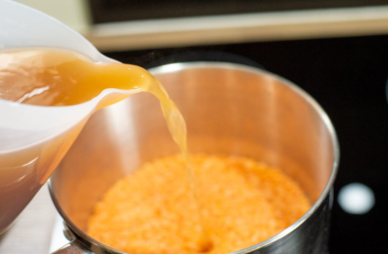pouring stock over lentils