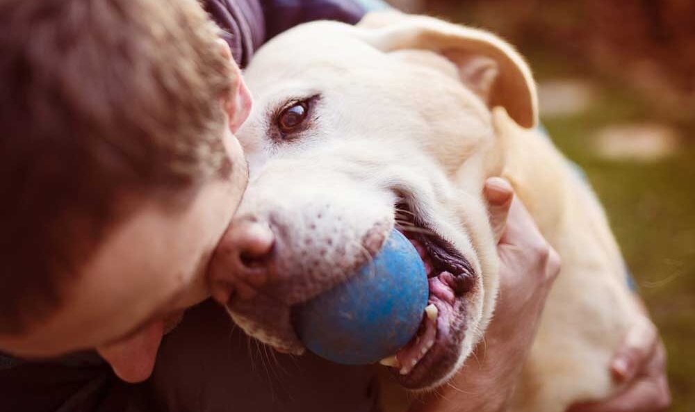 man cuddles his dog