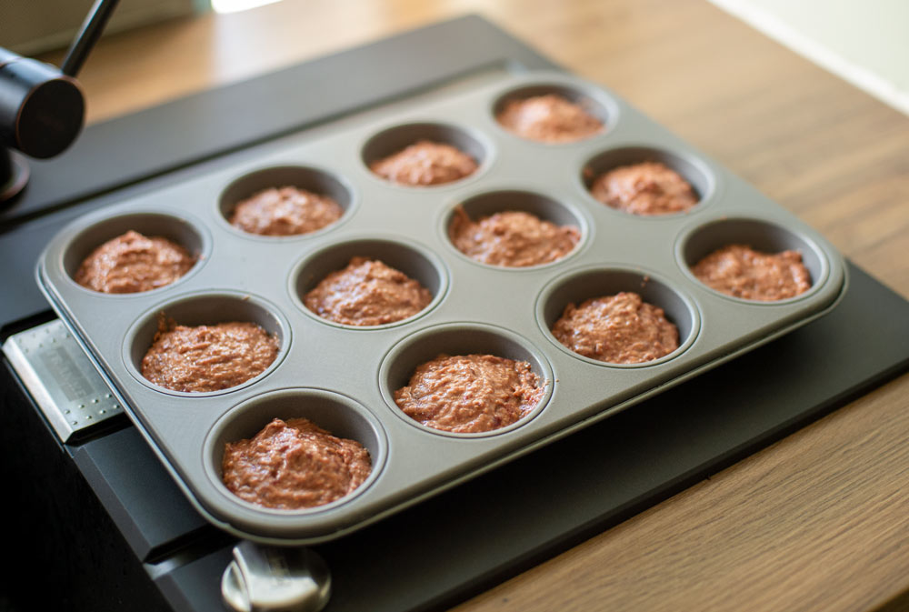 adding pupcake batter to cupcake tray